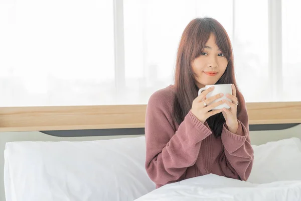 Asian women drinking coffee on bed in the morning — Stok fotoğraf