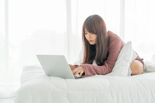 Asian women working with laptop on bed — 图库照片