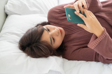 Asian women playing smartphone on bed 