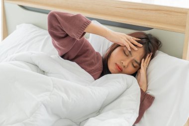 Asian women headache and sleeping on bed