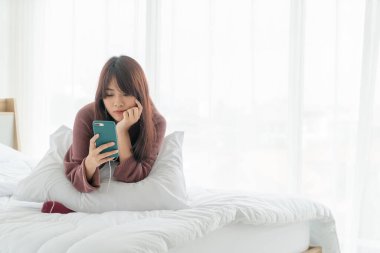 Asian women playing smartphone on bed 