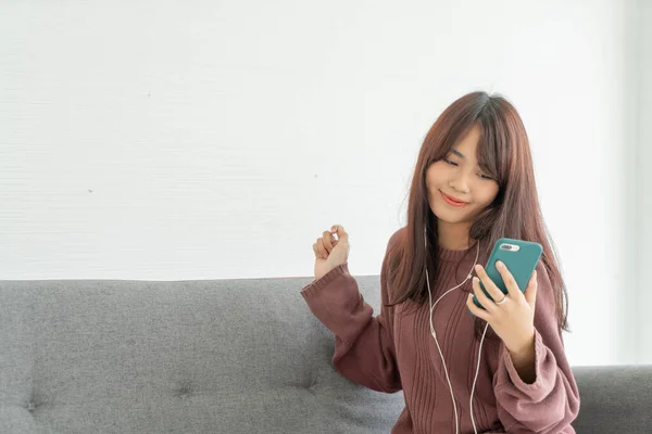 Mulher asiática usando smartphone no sofá cinza na sala de estar — Fotografia de Stock