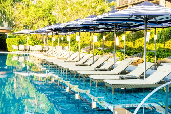 Guarda-chuva e cama de piscina em torno da piscina exterior no hotel reso — Fotografia de Stock