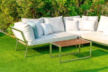 Bahçe sandalyesinde rahat yastıklar ve bahçede masa.