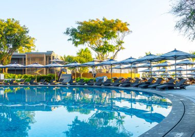 Seyahat tatili konsepti için otel otelinde yüzme havuzunun etrafında şemsiye ve havuz yatağı.