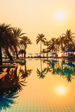 Şemsiye sandalyeli güzel palmiye ağacı gündoğumunda lüks otel tatil beldesinde - tatil ve tatil konsepti