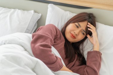Güzel Asyalı kadınların baş ağrısı ve yatakta uyuması.