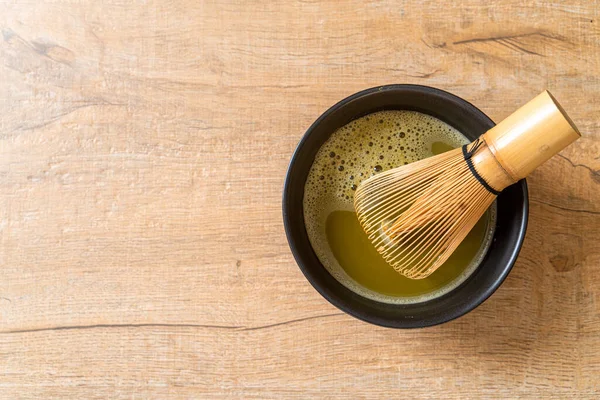 hot matcha green tea cup with green tea powder and bamboo whisk