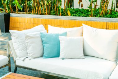 Bahçe sandalyesinde rahat yastıklar ve bahçede masa.