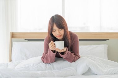 Güzel Asyalı kadınlar sabahları yatakta kahve içerler.