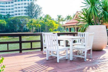 Beyaz veranda sandalyesi ve şemsiyeli masa.