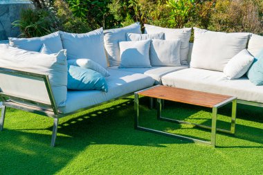 Bahçe sandalyesinde rahat yastıklar ve bahçede masa.