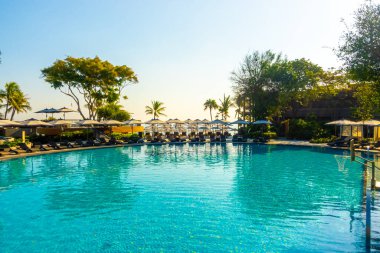 Seyahat ve tatil konsepti için otel otelinde yüzme havuzunun etrafında güzel bir havuz ve şemsiye.