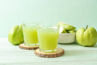 Taze guava suyu bardağı ve ahşap masada taze guava meyvesi.