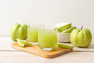 Taze guava suyu bardağı ve ahşap masada taze guava meyvesi.