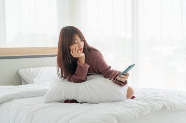 Güzel Asyalı kadınlar yatakta akıllı telefon oynuyorlar.