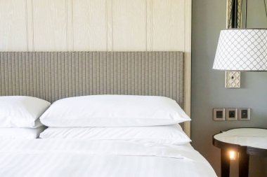 Yatak odasındaki beyaz yastıklar dekore edilmiş.