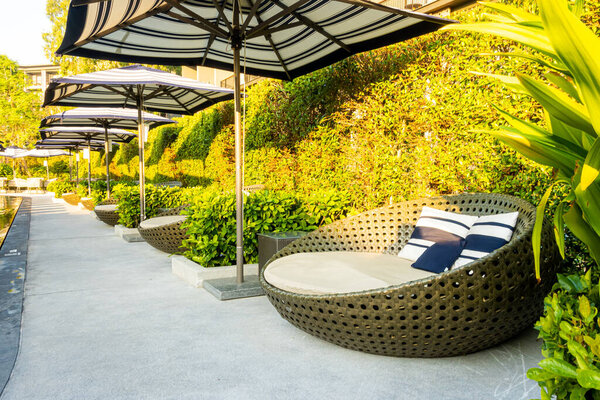 Зонтик и стул диван вокруг открытого бассейна в отеле курорта для путешествий концепции отдыха
