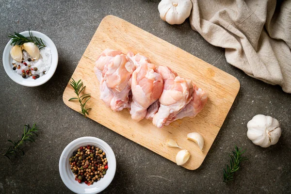 Taze çiğ tavuk kanatları (drumette veya baget çubuğu) ahşap tahtada malzemelerle birlikte.