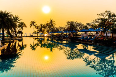 Şemsiye sandalyeli güzel palmiye ağacı gündoğumunda lüks otel tatil beldesinde - tatil ve tatil konsepti