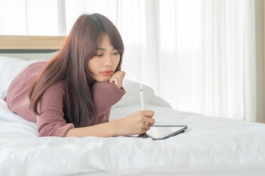 Yatakta tabletle çalışan güzel Asyalı kadınlar