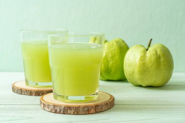 Taze guava suyu bardağı ve ahşap masada taze guava meyvesi.