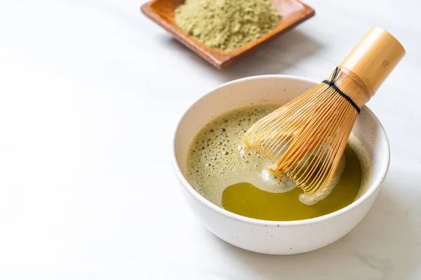 hot matcha green tea cup with green tea powder and bamboo whisk