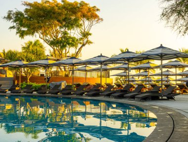 Seyahat tatili konsepti için otel otelinde yüzme havuzunun etrafında şemsiye ve havuz yatağı.