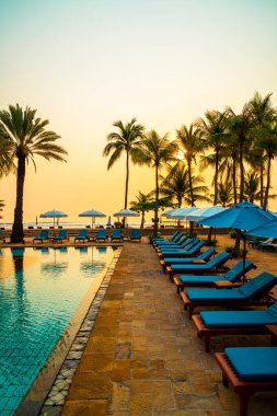 Şemsiye sandalyeli güzel palmiye ağacı gündoğumunda lüks otel tatil beldesinde - tatil ve tatil konsepti