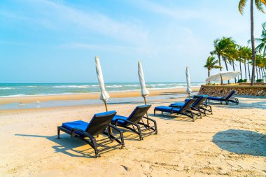 Sahilde deniz ve mavi gökyüzü arka planlı boş bir plaj sandalyesi.