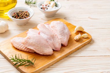 Tahtada taze çiğ tavuk kanatları ve malzemeler.