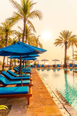 Şemsiye sandalyeli güzel palmiye ağacı gündoğumunda lüks otel tatil beldesinde - tatil ve tatil konsepti