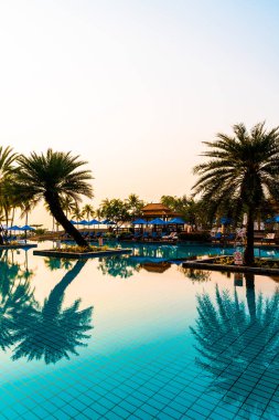 Şemsiye sandalyeli güzel palmiye ağacı gündoğumunda lüks otel tatil beldesinde - tatil ve tatil konsepti