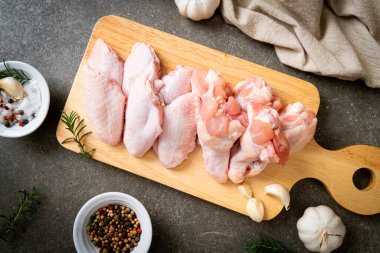 Tahtada taze çiğ tavuk kanatları ve malzemeler.