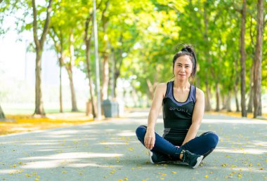 Parktaki egzersizden sonra Asyalı kadın oturuyor ve dinleniyor.