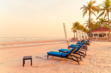 Sahilde deniz ve gökyüzü arka planlı boş bir plaj sandalyesi.