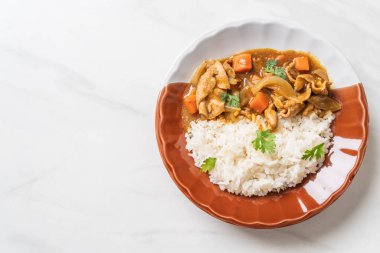 Dilimlenmiş domuz eti, havuç ve soğanlı Japon körili pilavı. Asya usulü.