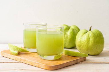 Taze guava suyu bardağı ve ahşap masada taze guava meyvesi.
