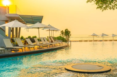 Tatil seyahati konsepti için deniz manzaralı havuzda yüzen şemsiye ve sandalye.
