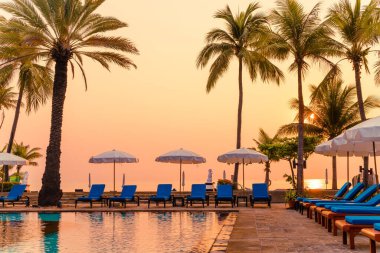 Şemsiye sandalyeli güzel palmiye ağacı gündoğumunda lüks otel tatil beldesinde - tatil ve tatil konsepti