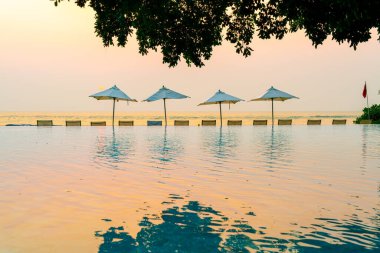 Tatil seyahati konsepti için deniz manzaralı havuzda yüzen şemsiye ve sandalye.