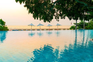 Tatil seyahati konsepti için deniz manzaralı havuzda yüzen şemsiye ve sandalye.