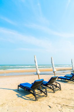 Sahilde deniz ve mavi gökyüzü arka planlı boş bir plaj sandalyesi.