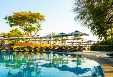 Güzel lüks şemsiye ve sandalye otel ve tatil konsepti için mavi gökyüzü ile yüzme havuzu etrafında etrafında