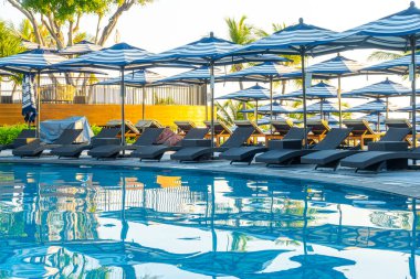 Seyahat tatili konsepti için otel otelinde yüzme havuzunun etrafında şemsiye ve havuz yatağı.