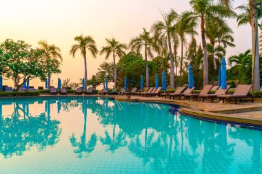 Gün batımında yüzme havuzunda şemsiyeli plaj sandalyesi ya da bilardo yatağı