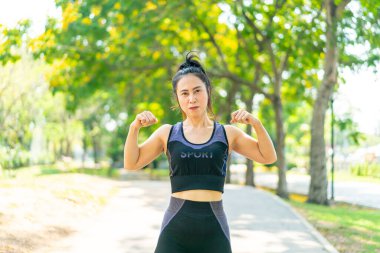 Parkta egzersiz yapmadan önce esneme hareketleri yapan Asyalı kadın.