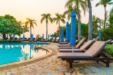 Gün batımında yüzme havuzunda şemsiyeli plaj sandalyesi ya da bilardo yatağı