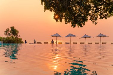 Tatil seyahati konsepti için deniz manzaralı havuzda yüzen şemsiye ve sandalye.