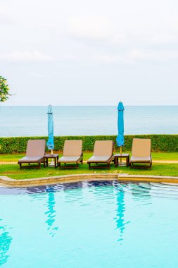 Sandalye havuzu ya da yüzme havuzu etrafında şemsiye olan yatak havuzu